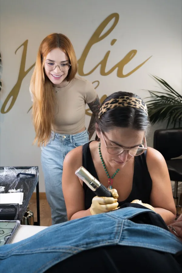 Julie supervisionando aluna tatuando